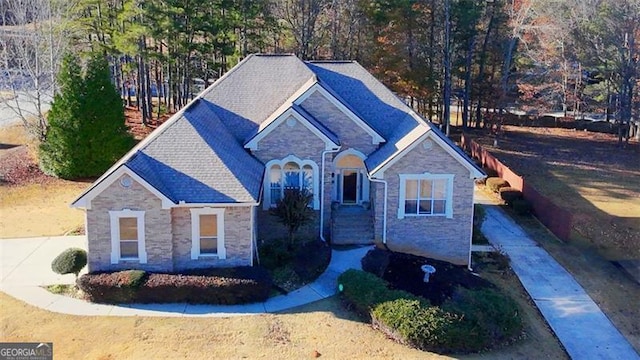 view of front of property with stone siding and roof with shingles