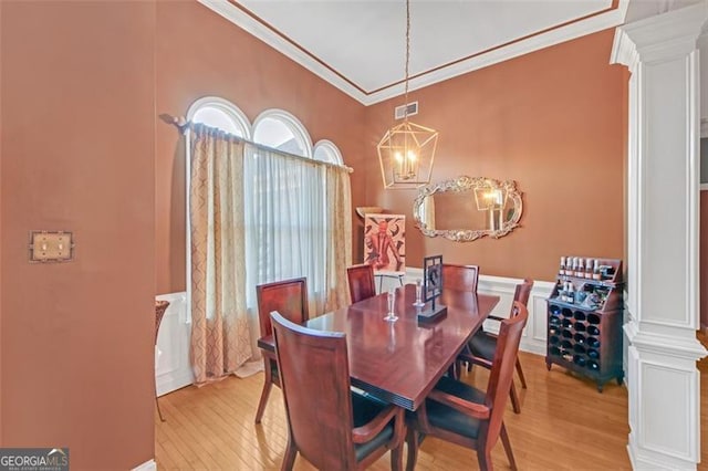 dining space with decorative columns, visible vents, light wood-style flooring, and crown molding