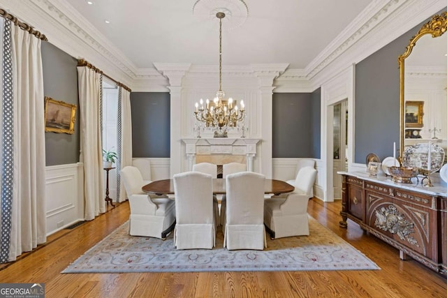 dining space with wood finished floors, a wainscoted wall, and an inviting chandelier