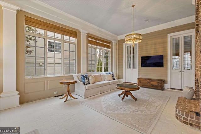 living room with ornate columns, brick floor, and crown molding