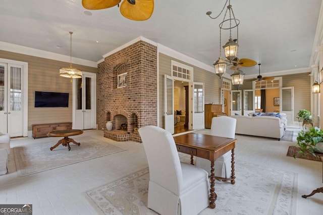 dining space featuring brick floor, an outdoor brick fireplace, crown molding, and a ceiling fan