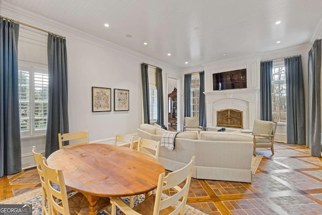 dining space with a healthy amount of sunlight, a brick fireplace, crown molding, and recessed lighting