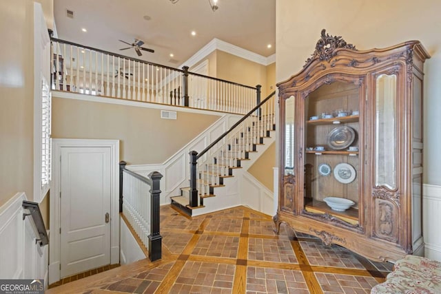 foyer with a decorative wall, recessed lighting, a high ceiling, visible vents, and crown molding