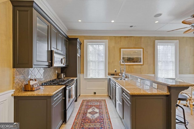 kitchen with tasteful backsplash, light stone counters, a breakfast bar area, stainless steel appliances, and a sink