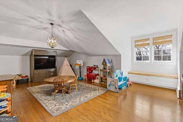 playroom with lofted ceiling, a notable chandelier, and wood finished floors