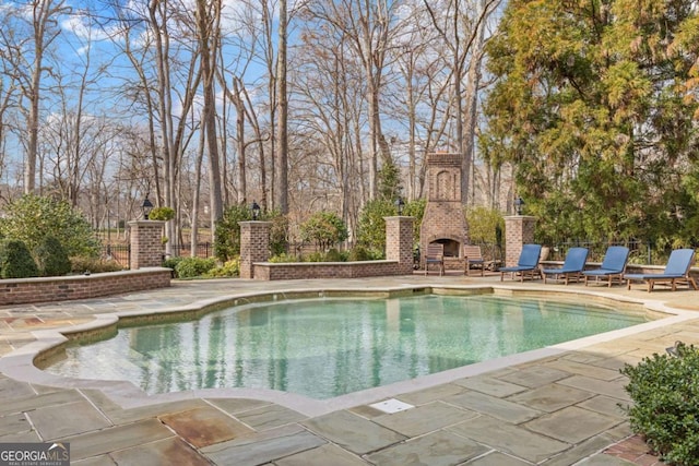 view of pool featuring an outdoor brick fireplace, a patio area, fence, and a fenced in pool