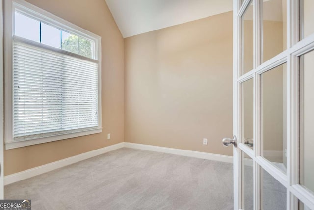 empty room with lofted ceiling, french doors, carpet flooring, and baseboards