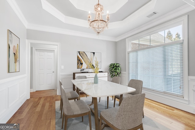 dining area featuring a tray ceiling, visible vents, a notable chandelier, and light wood finished floors