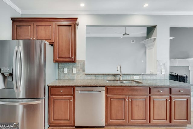 kitchen featuring ceiling fan, light stone counters, a sink, appliances with stainless steel finishes, and brown cabinetry