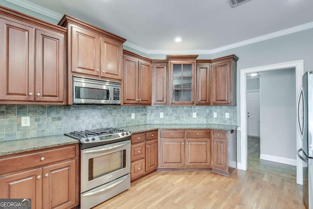 kitchen featuring stainless steel appliances, ornamental molding, light stone countertops, light wood finished floors, and tasteful backsplash