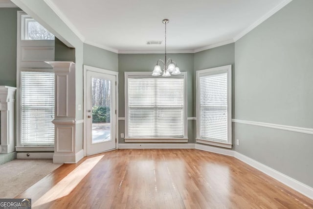 unfurnished dining area with baseboards, visible vents, a chandelier, and crown molding