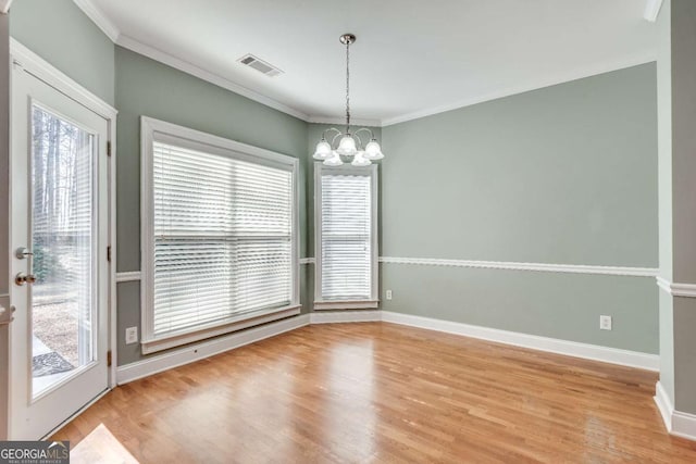 unfurnished dining area featuring crown molding, visible vents, a chandelier, and wood finished floors