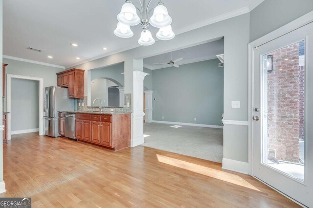2477 Misty Rose Ln, Loganville, GA 30052 - kitchen featuring light wood-type flooring, brown cabinets, a sink, arched walkways, and appliances with stainless steel finishes