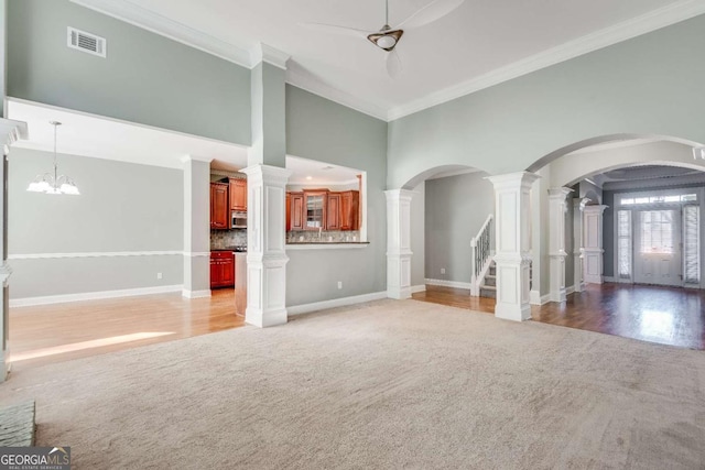 unfurnished living room with light carpet, ornamental molding, a high ceiling, and visible vents