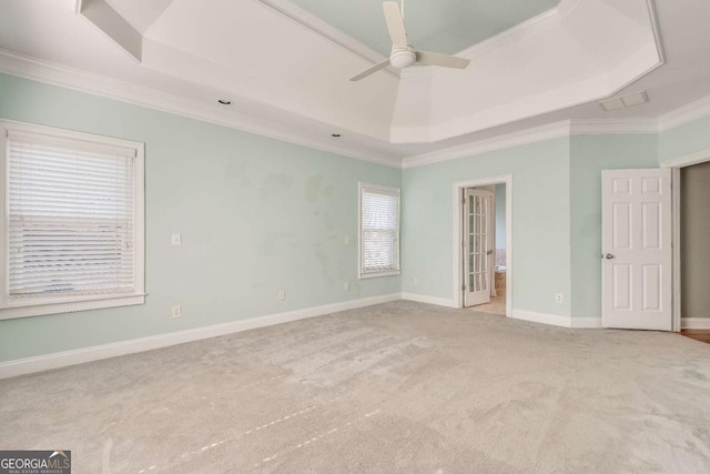 unfurnished bedroom featuring carpet floors, baseboards, a raised ceiling, and ornamental molding