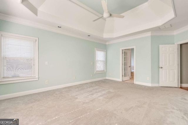 unfurnished room with ceiling fan, carpet flooring, baseboards, ornamental molding, and a raised ceiling