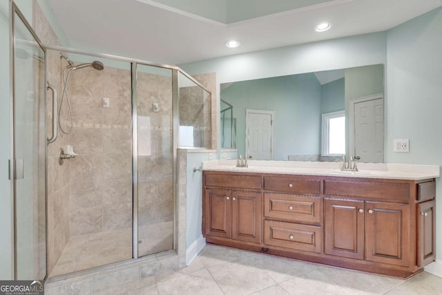 full bathroom featuring double vanity, a stall shower, a sink, and tile patterned floors