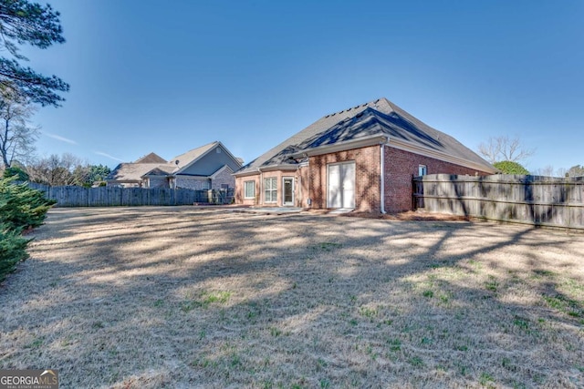 exterior space featuring a yard, brick siding, and fence