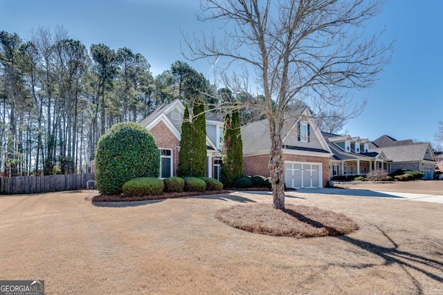 view of front of house featuring a garage, concrete driveway, brick siding, and fence