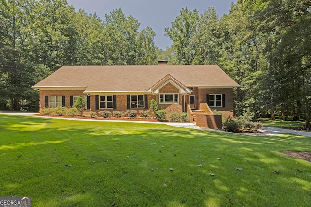 single story home featuring brick siding, a chimney, and a front lawn