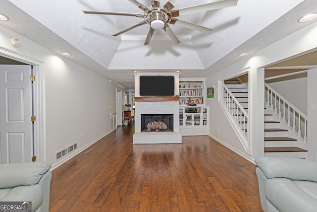 unfurnished living room with built in features, stairway, a textured ceiling, and hardwood / wood-style floors