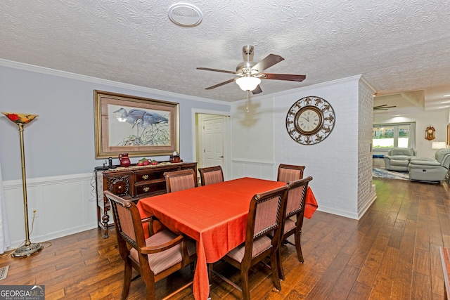 dining area with dark wood-style flooring, wainscoting, and crown molding