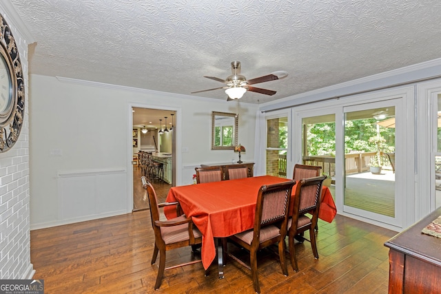 dining room with ceiling fan, ornamental molding, dark wood finished floors, and a textured ceiling