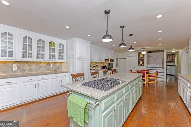 kitchen with white cabinetry, stainless steel gas stovetop, green cabinetry, and hardwood / wood-style flooring