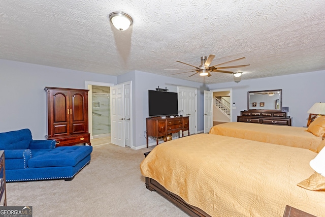 bedroom featuring light colored carpet, connected bathroom, a textured ceiling, and baseboards