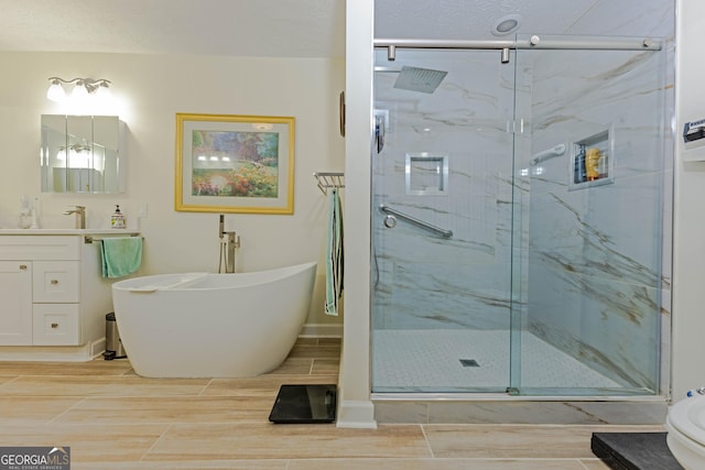 full bath featuring a soaking tub, a marble finish shower, wood finish floors, and vanity