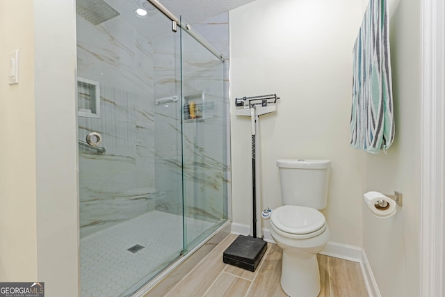 bathroom with wood tiled floor, a marble finish shower, baseboards, and toilet