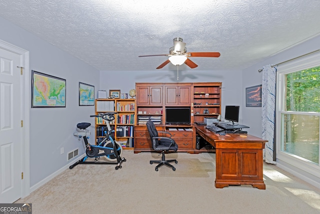 office featuring carpet, visible vents, ceiling fan, and a textured ceiling