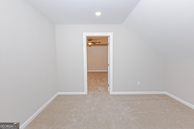 carpeted empty room featuring baseboards and vaulted ceiling