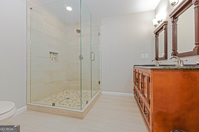 full bathroom with toilet, a stall shower, double vanity, and baseboards