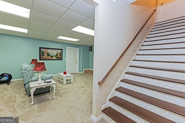 staircase with carpet floors, a drop ceiling, and baseboards