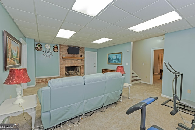 carpeted living area featuring a brick fireplace, a drop ceiling, baseboards, and stairs