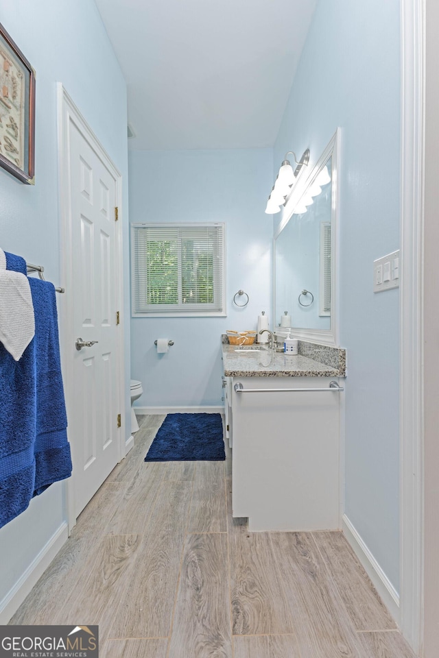 bathroom with vanity, wood finished floors, toilet, and baseboards