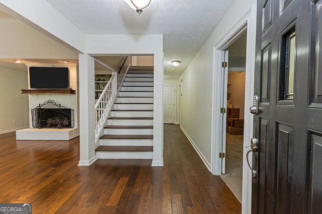 interior space featuring a textured ceiling, stairs, a fireplace, and hardwood / wood-style floors