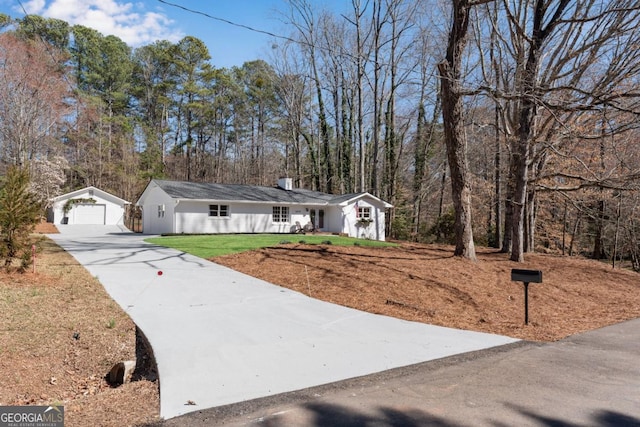 single story home with an outbuilding, a front lawn, a chimney, and a garage