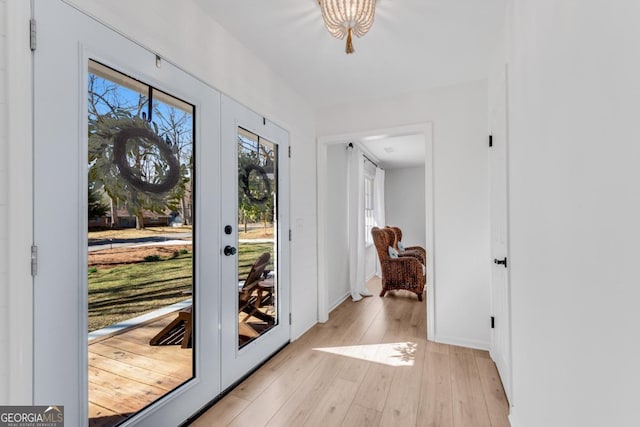 doorway to outside with baseboards, french doors, and light wood-style floors