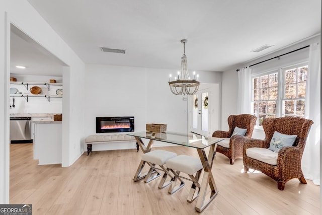 dining room with a glass covered fireplace, visible vents, and light wood finished floors