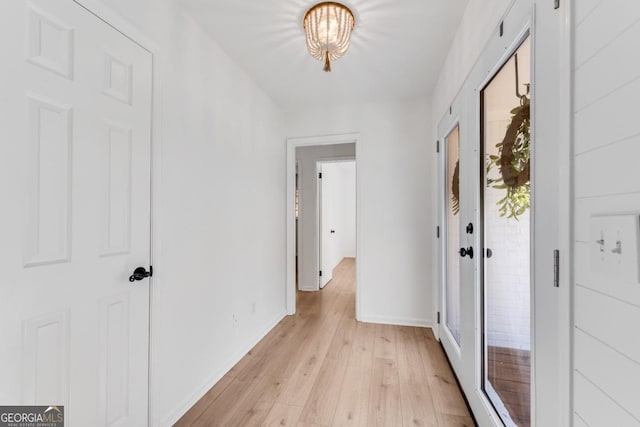 corridor with light wood-style flooring and baseboards