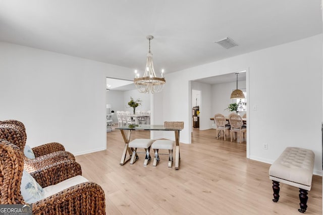 dining space with light wood-type flooring, baseboards, visible vents, and a notable chandelier