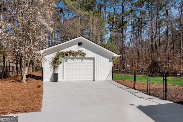 detached garage featuring driveway and fence