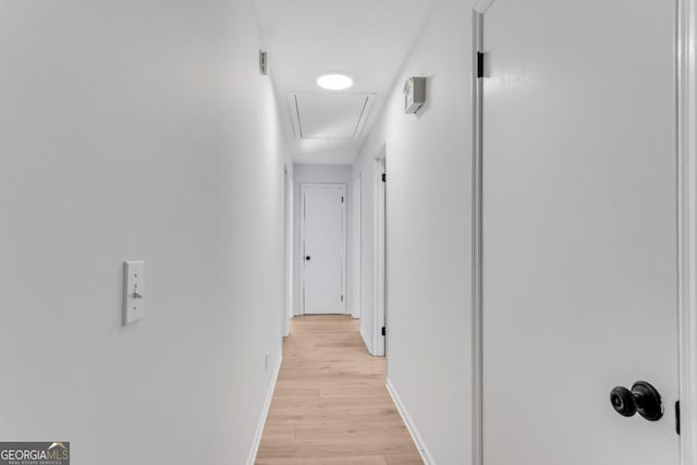 hall featuring light wood finished floors, attic access, and baseboards