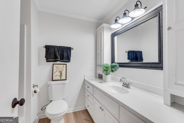 bathroom featuring toilet, wood finished floors, vanity, baseboards, and ornamental molding