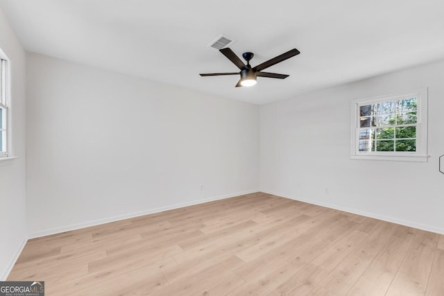 empty room with light wood-type flooring, visible vents, and baseboards