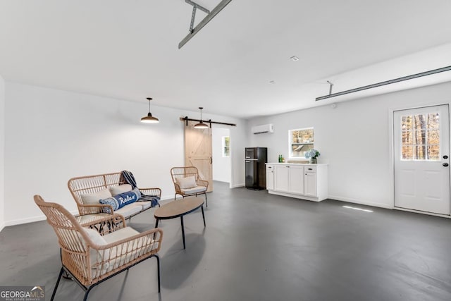 sitting room with a wall mounted AC, plenty of natural light, finished concrete flooring, and a barn door