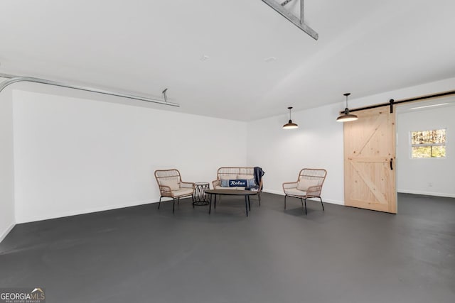 living area with finished concrete flooring, a barn door, and baseboards