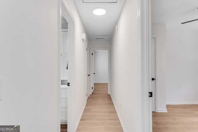 hallway with attic access, baseboards, and light wood finished floors